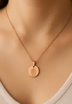 Pendentif médaillon souvenir en or rose porté autour du cou.