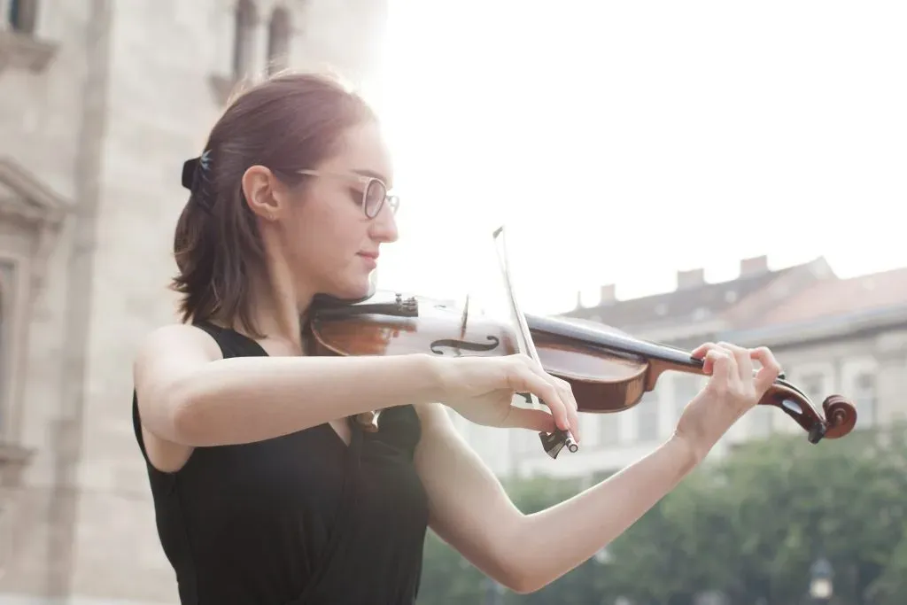 Jeune femme jouant du violon en extérieur pour l'accompagnement musical d'une cérémonie.