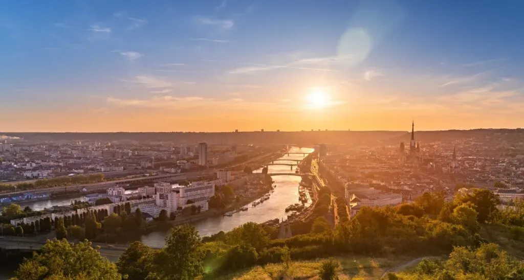 Panorama aérien de la ville de Rouen et de la Seine baignée par le soleil couchant.