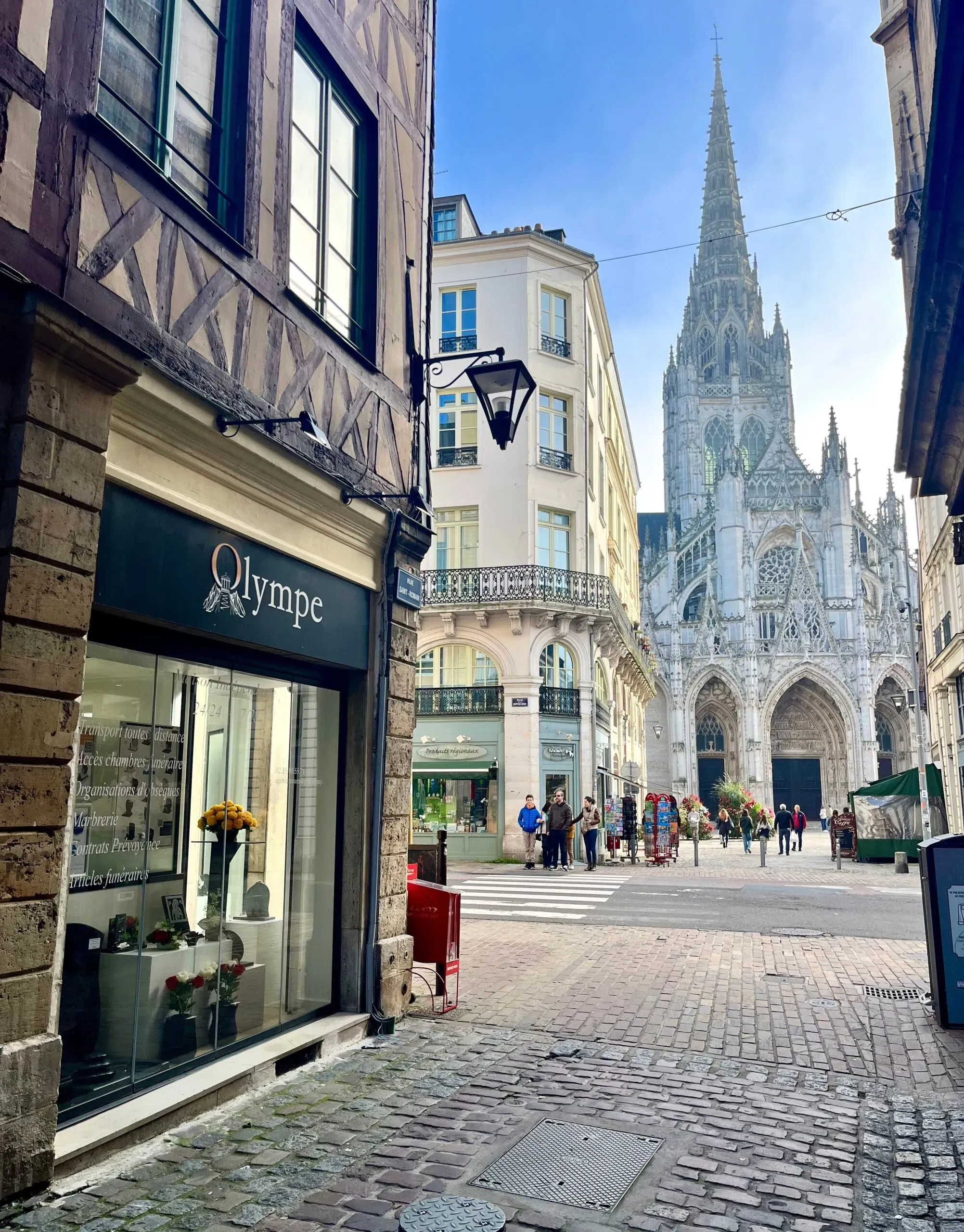 Agence Olympe Pompes Funèbres dans une rue pavée avec vue sur la cathédrale de Rouen.